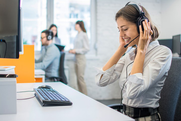 Portrait of young attractive happy smiling female customer support phone operator at modern office workplace