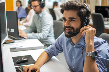 Portrait of happy smiling customer support phone operator in headset at office