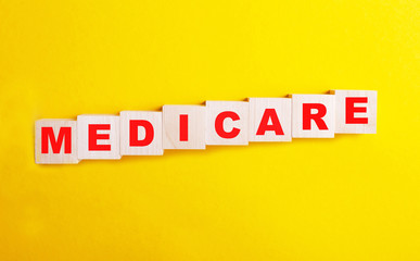 Medicare word written on cube shape wooden blocks on yellow table