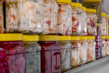 Traditional homemade pickles in plastic jar of various fruits and vegetables