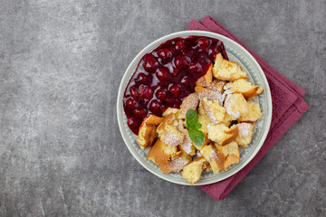 Kaiserschmarren or Kaiserschmarrn is a traditional Austrian or German sweet pancake dessert, with icing sugar and berry, cherry sauce or rote grutze jam. Top view. Copy space.