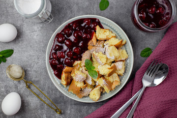 Kaiserschmarren or Kaiserschmarrn is a traditional Austrian or German sweet pancake dessert, with icing sugar and berry, cherry sauce or rote grutze jam. Top view. 