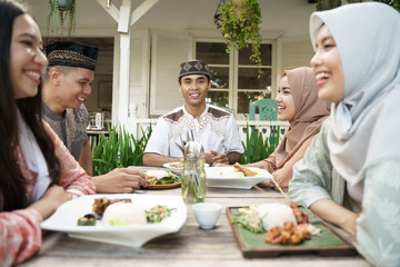 friend and family sitting together while waiting for iftar dinner time or breaking the fast during ramadan kareem. muslim iftar dinner