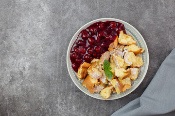 Kaiserschmarren or Kaiserschmarrn is a traditional Austrian or German sweet pancake dessert, with icing sugar and berry, cherry sauce or rote grutze jam. Top view. Copy space.