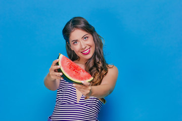 Pretty girl happily eating watermelon on a blue background