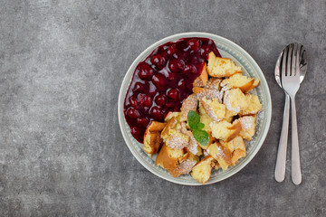 Kaiserschmarren or Kaiserschmarrn is a traditional Austrian or German sweet pancake dessert, with icing sugar and berry, cherry sauce or rote grutze jam. Top view. Copy space.