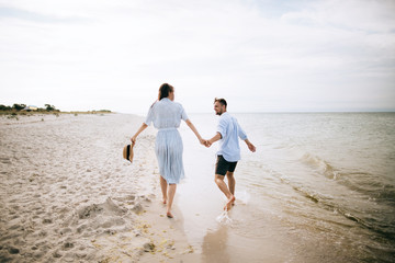 Fototapeta na wymiar young happy couple walking on sea beach