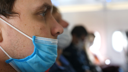 Man traveling at plane with wearing protective medical mask. Concept virus protection coronavirus pandemic covid-19