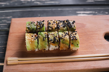 Sushi with salmon on a wooden board on a dark wooden background
