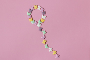 Pastry multicolored sprinkles-butterflies are laid out in the shape of a balloon on a pink background. Decoration of confectionery products.