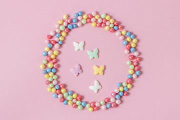 Pastry sprinkles are scattered in the form of a circle, inside it are enclosed colorful butterflies...