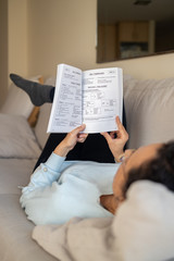 Pretty spanish woman sitting on the sofa, learning english at home