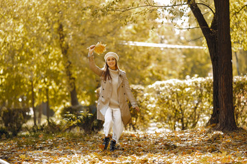 Girl in a brown coat. Woman in a autumn park. Lady with a leaf.