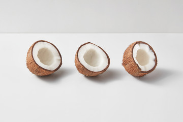 Set from three tropical natural halves of coconut on a light grey background.