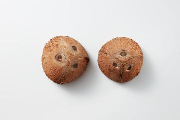 Two whole parts of brown natural tropical coconut fruit on a grey background.