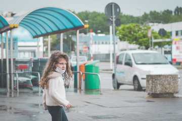 little girl wearing surgical mask near  a supermarket in italy