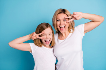Photo of two people young beautiful mom lady small daughter good mood showing v-sing symbols near eyes saying hi friends wear casual white s-shirts isolated blue color background - obrazy, fototapety, plakaty