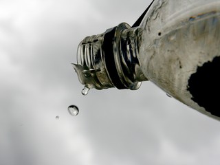 A drop of water drips from the neck of the bottle.