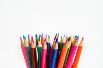 A lot of colored pencils on a light background. Bright and colorful pencils close up