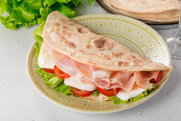 Italian flatbread - Piadina (Piada or piadina romagnola)  with mozzarella cheese, salad, tomatoes...