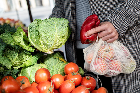 man using reusable mesh bags at a greengrocer