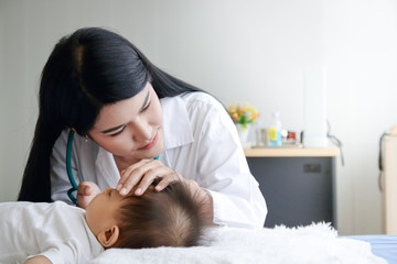 Female doctor examines the Asian little boy patient in bed in a clinic. Health care concept. copy space