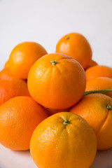 Pile of whole oranges with green leaf isolated on white background. Closeup, vertical shot. Natural vitamin or organic food concept