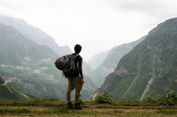 Senderista joven de espaldas observando las montañas en el Cañon del Colca en Peru