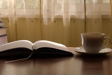 a diary and a cup of tea on the table on a sunny morning