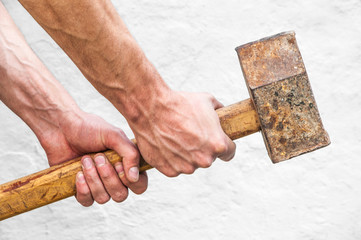 sledgehammer in the hands. man holds a big iron hammer. building tool on a light background