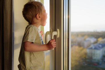 Child opening window without parents. Dangerous situation