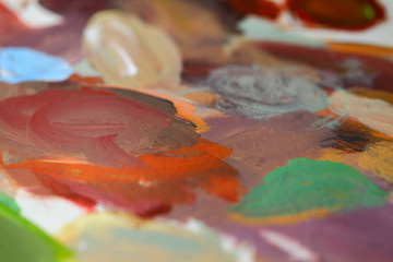 A palette with mixed multi-colored oil paints, an image with a bokeh effect.