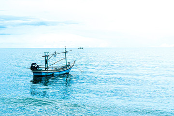 Small fishing boat floating in blue sea with blue sky, Thailand Fishing boat or fisherman boat or ship on Sam Roi Yod bech Prachuap Khiri Khan Thailand with blue sky and cloud and blue sea