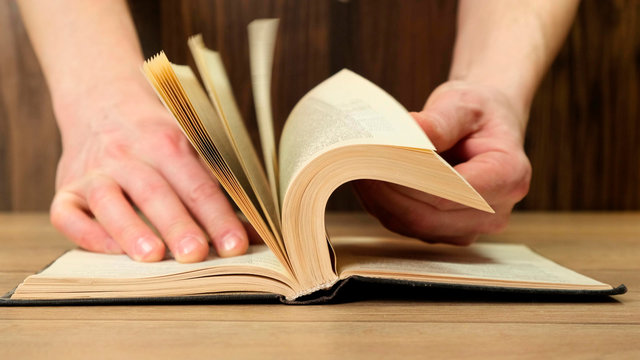 Man flipping pages in book for browsing. Close up.