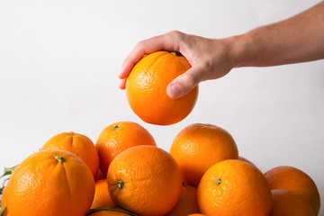 Person taking orange from top of fruits heap isolated on white background. Cropped shot, side view. Healthy nutrition or organic food concept
