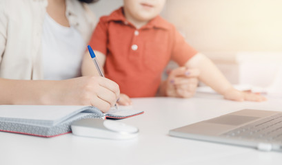 Woman on maternity leave working home online with laptop in kitchen with small child. Concept mom...