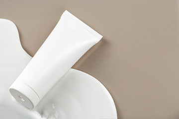 Blank white skincare product tube on beige background with copy space