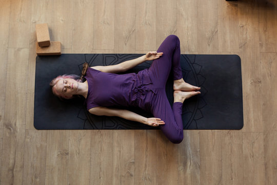 Modern girl is doing home yoga exercise. Lying on  floor Supta Baddha Konasana. Zen relaxation after sports. Top view. resting. Stretching Fitness Studio Online yogini trainer. silence meditation