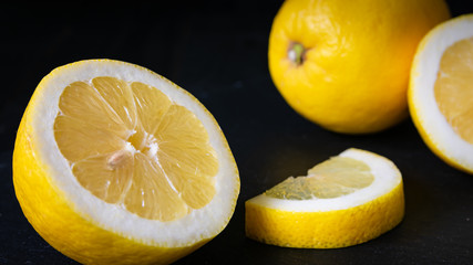 Sliced yellow lemon on black background close up. Food background. Flat lay. Juicy ripe fresh citrus fruit lemon