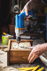 Carpenter making wooden insect house. Craftsperson using drill in workshop