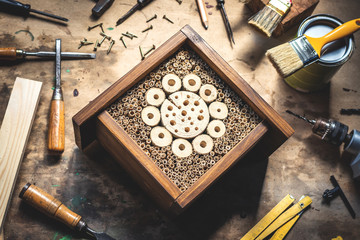 Insect hotel or house on wooden table at workshop. Homemade craft product