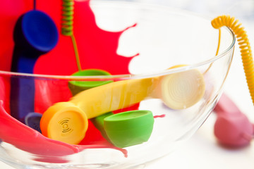 Colored telephone handsets in glass jar, symbolic communication