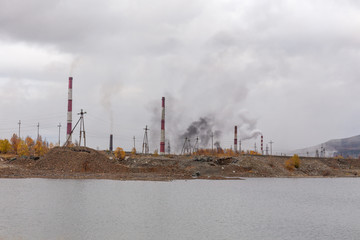 Smoke and ecology. pipes of thermal power plants against a blue sky. A stream of black smoke comes out of the right pipe