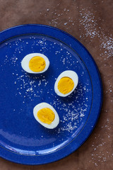 Fototapeta na wymiar three half eggs on a blue plate with salt