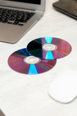 cd, dvd on office desk with mouse and laptop
