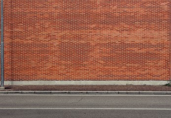 High brick wall with a porphyry sidewalk and an asphalt street in front. Urban background for copy...