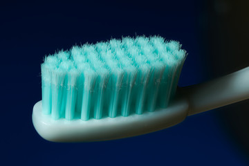 white toothbrush with aquamarine bristles on a black blue background