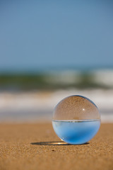 Fototapeta na wymiar 海の海岸にある透明な水晶ガラスボール