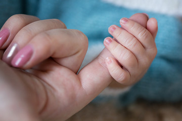 the hand of the baby on the mother's finger close-up