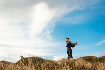 lonely guy posing in jacket fluttering on mountains wind travel touristic life style concept photography highland environment and cloudy sky background